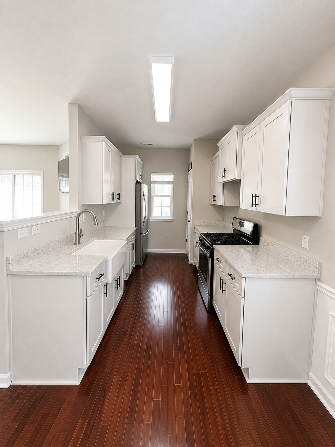 Finished galley kitchen remodel with white cabinets, black hardware, and stone counters