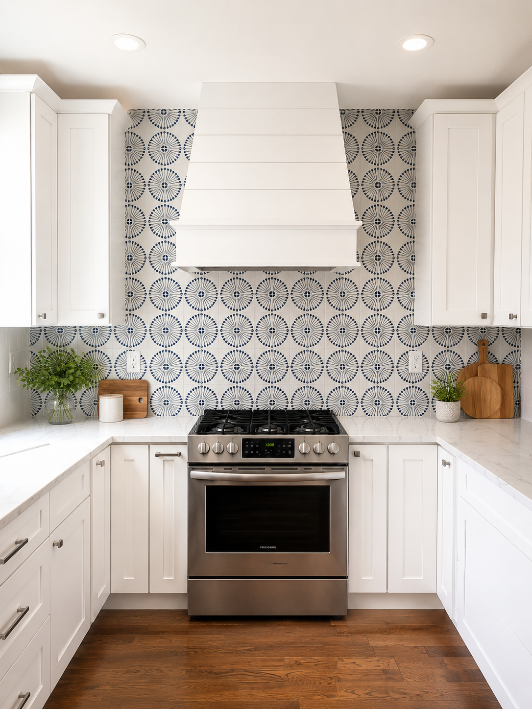 White kitchen remodel with a patterned blue and white tile backsplash and custom range hood